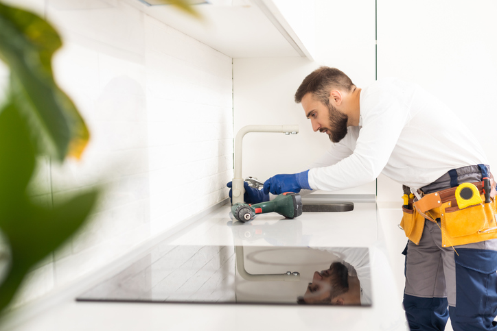 plumber installs kitchen faucet. refurbishment in the apartment.